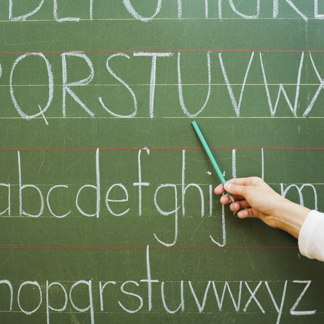 Hand zeigt auf Buchstaben auf einer grünen Tafel.