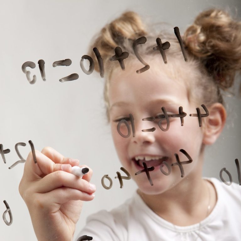 Ein Kind löst mathematische Aufgaben auf einer beschlagenen Scheibe.